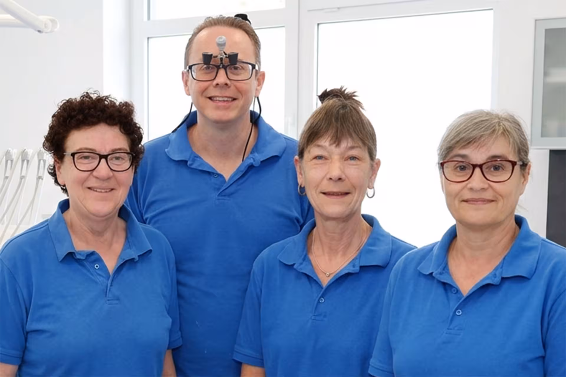 Det samlede tandlægeteam i blå kliniktøj smiler til kameraet i Værløse